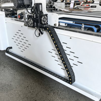 Side mounted flexible plastic drag chain on white automated machinery frame