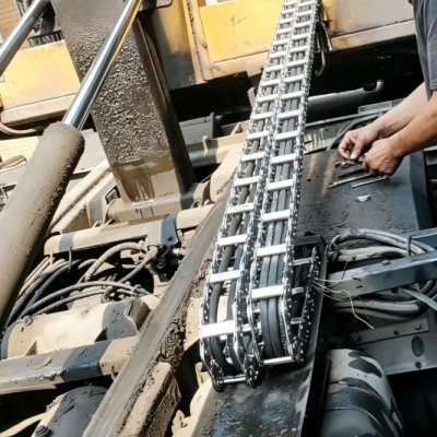 Engineer installing heavy duty steel drag chain on outdoor engineering machinery