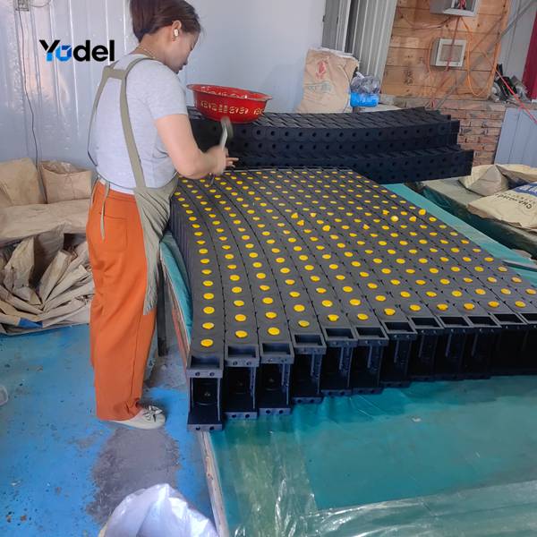Factory technician manually assembling 35x100 nylon cable drag chain links on workbench