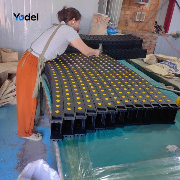 Factory worker manually assembling drag chain 45x100 nylon links on workshop table