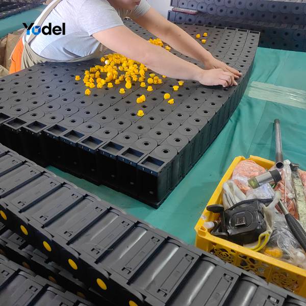 Factory technician assembling enclosed drag chain 35*90 links and yellow side pins on production table