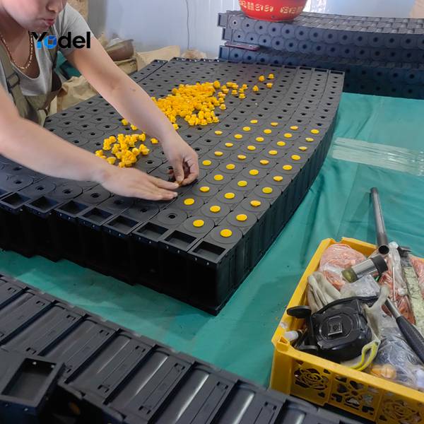 Factory technician assembling nylon drag chain 45x150 links and yellow dots on assembly workbench