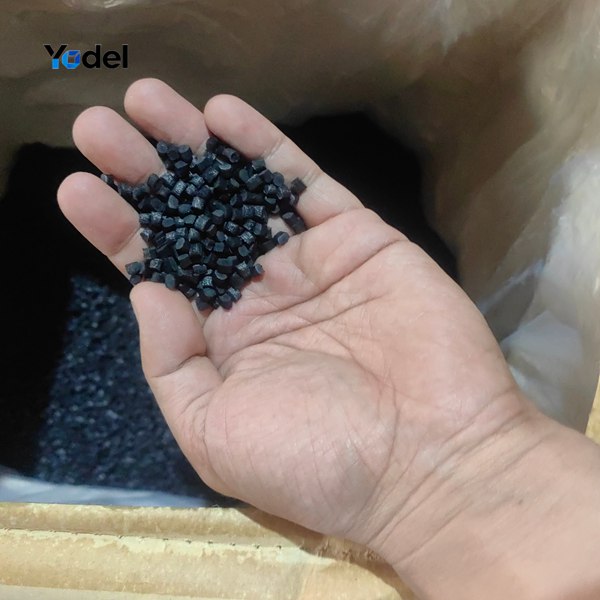 Hand holding pure virgin PA66 black nylon granules used for molding high-strength plastic cable chain 25x38 links